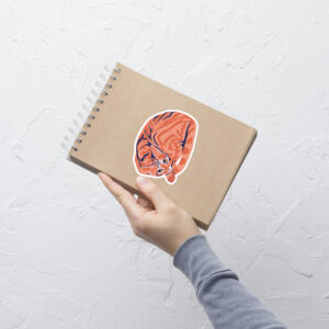 Orange Feline Relaxing: Ginger Tabby Cat Sticker displayed on a notebook