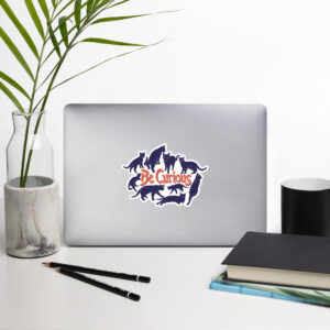Curiosity Cats: Be Curious Sticker (Orange & Violet) on a laptop